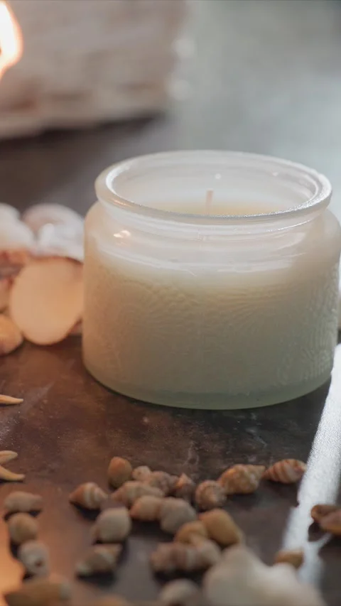 Close up of lit scented candle with seashells and starfish in soft indoor Stock Footage 344680052