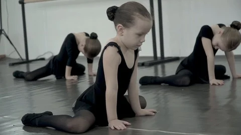 Close-up little ballet dancer trying to copy movement and warming up in dance Video stock 113529536