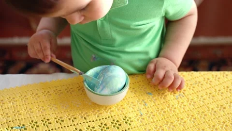 Close-up of a little boy painting Easter egg with paint and brush Stock Footage 177935244