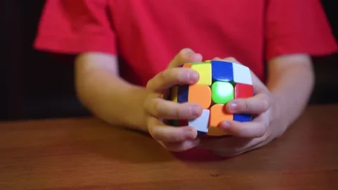 Close up of little boy plays a developmental mind and quick wit toy Rubik's Cube Video stock 146739412