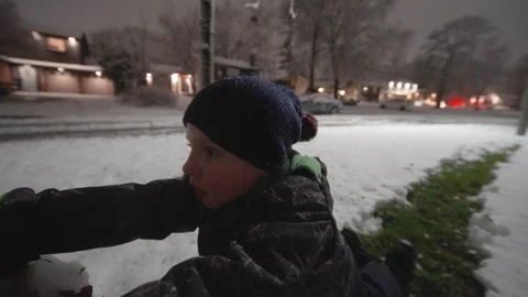Close-up little boy rolling a large snowball on a winter evening. Stock Footage 157424156