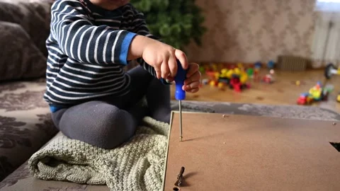 Close up of a little boy screw the screws with a screwdriver. Stock Footage 162300525