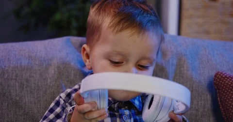 Close up of the little boy trying to take on big headphones and listen to the Stock Footage 82920054
