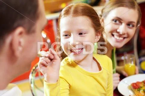Close-up of a little girl feeding her father with spoon and smiling Stock Photos