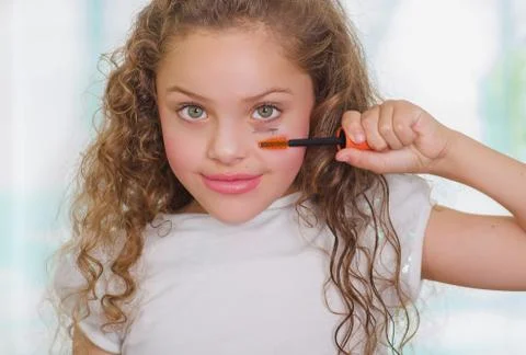 Close up of little girl using wrong an eye mascara in her face in a blurred Stock Photos