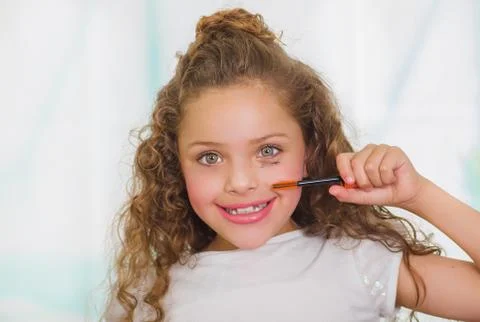 Close up of little girl using wrong an eye mascara in her face in a blurred Stock Photos