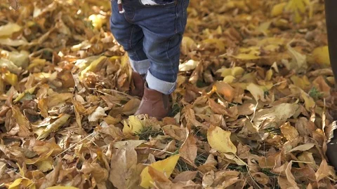 Close-up A little one-year-old boy, with his mother, in brown boots and blue Stock Footage 119106479