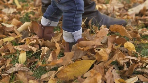 Close-up A little one-year-old boy, with his mother, in brown boots and blue Stock Footage 119254772