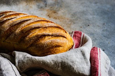 Close-up of a loaf of bread and a tea towel on a table Stock Photos