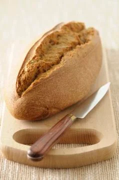 Close-up of Loaf of Bread with Knife on Cutting Board on Beige Background, Stock Photos