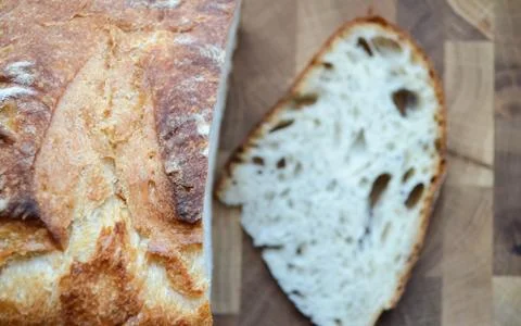 Close-up loaf of fresh bread on a blurred background of a cut heap of bread. Stock Photos