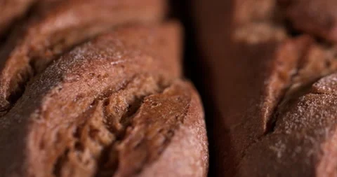 Close-up loaf in a row lies on a table in smoke on a black background Stock Footage 130361773