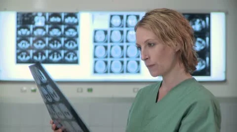 Close-up lockdown shot of a doctor in surgical scrubs studying an x-ray image Stock Footage