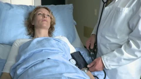 Close-up lockdown shot of a doctor taking the blood pressure of a female patient Stock Footage