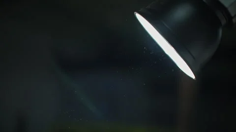 Close-up of a lone spotlight casting a bright beam into a dark room, revealing Video stock 333839405