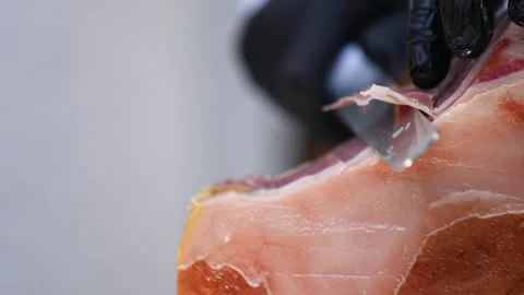 Close-up of a long knife slicing bacon. A long knife is used to slice jamon into Stock Footage 325739584