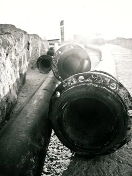 Close up of long pipes lying down on the ground near a wall in Tel Aviv port Foto stock