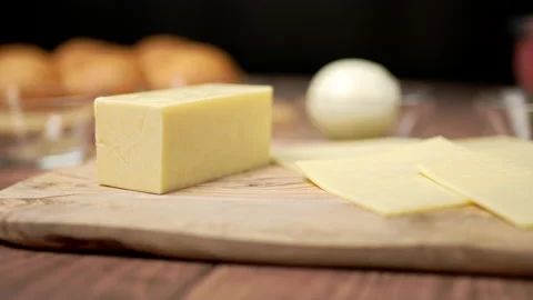 Close-up look a big piece of hard cheese and sliced cheese on a wooden board. Stock Footage 135308896