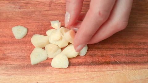 A close-up look of chopping garlic cloves on a wooden cutting board in 4K. Stock Footage 141304101