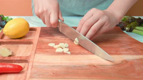 A close-up look of chopping garlic cloves on a wooden cutting board in 4K. Stock Footage 141304455