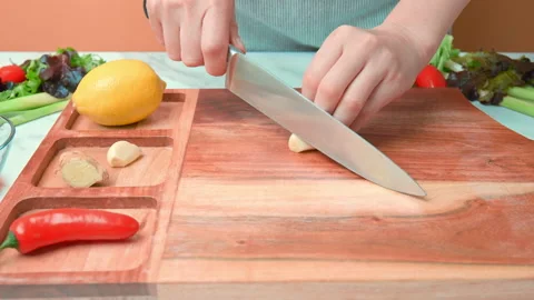 A close-up look of chopping garlic cloves on a wooden cutting board in 4K. Stock Footage 141304456