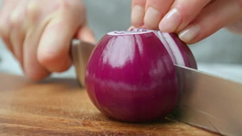 A close-up look of cutting a red onion in half with a chef knife in slow-motion. Stock Footage 142822498