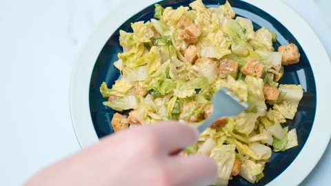 A close-up look of female hands serving with a fork fresh Caesar Salad in 4K. Stock Footage 140770001