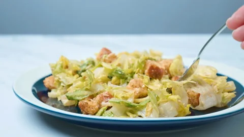 A close-up look of female hands serving with a fork fresh Caesar Salad in 4K. Stock Footage 140770044