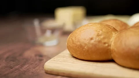Close-up look of freshly baked bread rolls on a wooden cutting board. Stock Footage 135310117