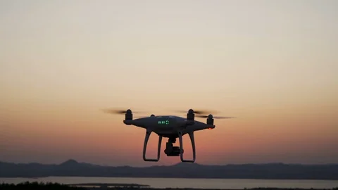 Close look of hovering quadcopter drone filming the sunset landscape Stock Footage 115638671