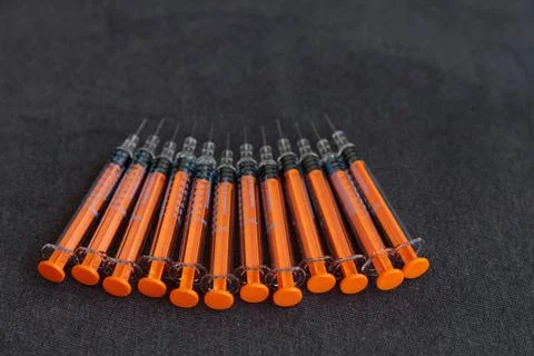 A Close-Up Look at Multiple Syringes Lined Up Neatly on a Dark Background Stock Photos