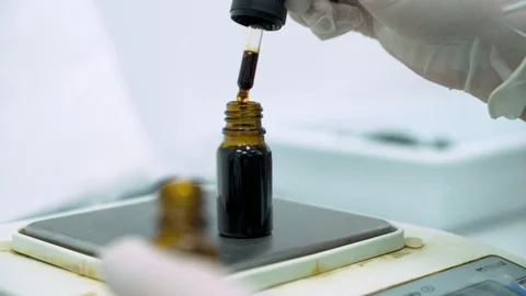 Close look of Scientists hand using Dropper and filling bottle with Cbd Oil on Stock Footage 116611929