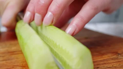 A close-up look of slicing and chopping a big green cucumber on a cutting board. Stock Footage 142111603