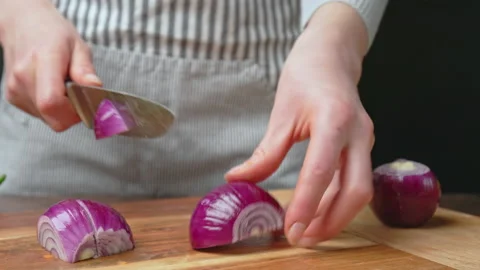 A close-up look of slicing the red onion on a wooden cutting board in 4k. Stock Footage 145114785