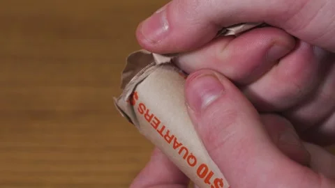Close up look at someone unwrapping a roll of USD Quarters. Vidéo 333286629