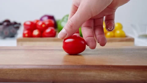 A close-up look of woman's hand spinning Cherry Tomatoes on cutting board in 4k Stock Footage 142107552