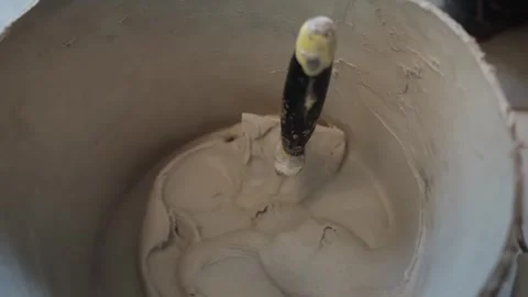 Close-up looking into a bucket of mixed tile adhesive with a hand trowel Stock Footage 345833919