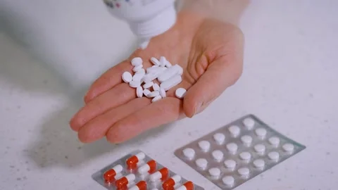 Close-up, lots of white pills fall into a woman's hand from a medical jar Stock Footage 235518918