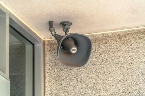 Close up of a loud speaker at the white ceiling at the exterior of a building Foto stock