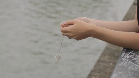Close up of a love pendant handled by Attractive sad blue-eyed model woman with Video stock 110762353