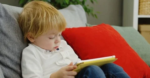 Close up of the lovely little boy using his tablet device for watching cartoons Stock Footage 82916235