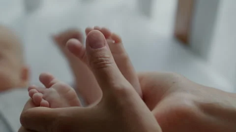 Close-up loving mother holds tiny feet of her newborn baby Stock Footage 306000177