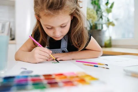 Close up low angle image of a little girl painting with watercolor Stock Photos
