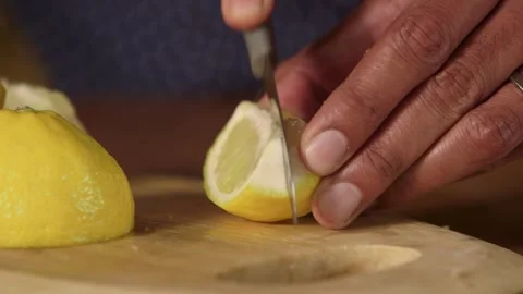 Close-Up Low Angle of Male Hands Chopping Fresh Zesty Lemon in Rustic Setting" Stock Footage 296833721