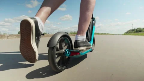 CLOSE UP, LOW ANGLE: Person riding on a scooter Pushing off with left foot 스톡 동영상 132793756