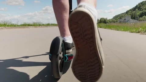 CLOSE UP, LOW ANGLE: Person riding on a scooter Pushing off with right foot Stock Footage 132793844