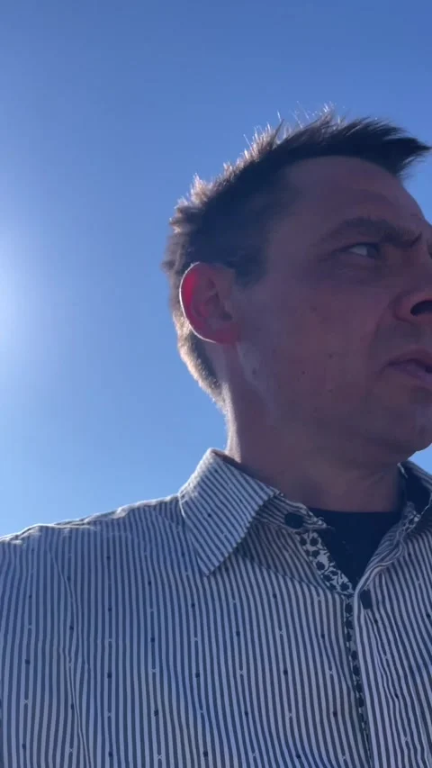 Close low-angle portrait of middle aged man outdoors against blue sky Stock Footage 341672339
