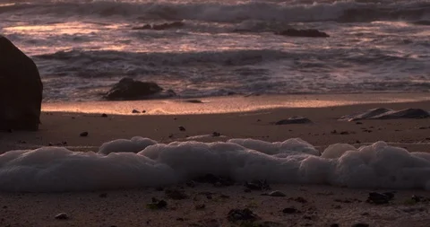 Close up, low angle shot of foam on beach at dusk with waves in background Stock Footage 116586206