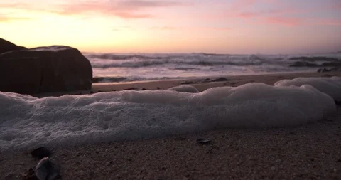 Close up, low angle shot of foam on beach at dusk with waves breaking 動画素材 116586755
