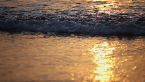 Close Up Low Angle Shot of Gentle Sea Waves on Wet Sand at Sunset Video stock 345775541